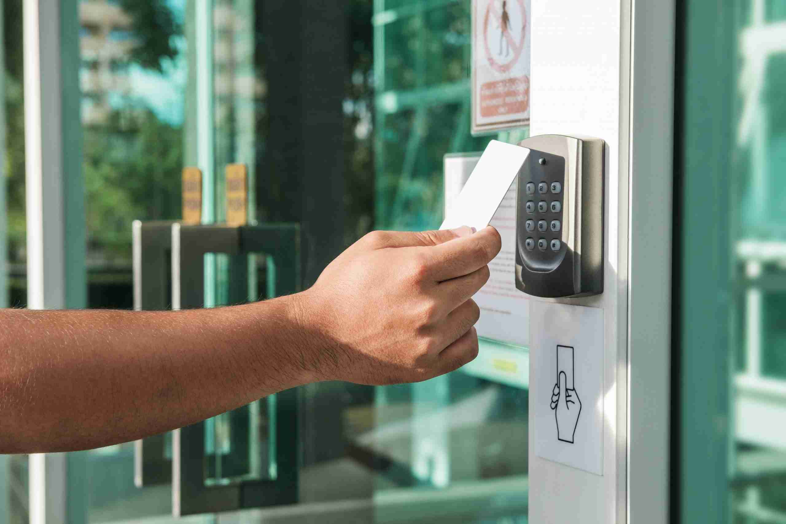 hand using keycard on electronic access control panel to enter a door