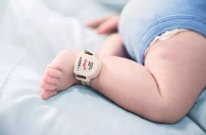 infant wearing hugs tag